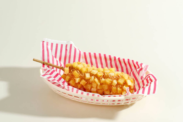 Delicioso crujiente estilo coreano Chunky Potato Corn Dogs con masa y papas fritas. Aislado en fondo crema con espacio de copia para texto - Foto, imagen