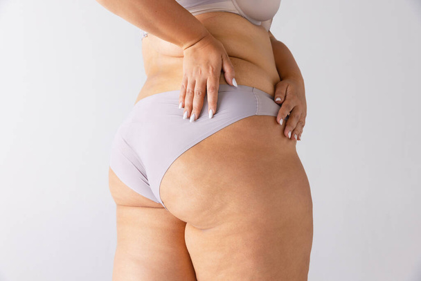 Image of plump, female body, buttocks in underwear isolated over grey background. Weight loss. Anti-cellulite treatment. Concept of beauty, body and skin care, health, plastic surgery, cosmetics, ad - Photo, Image