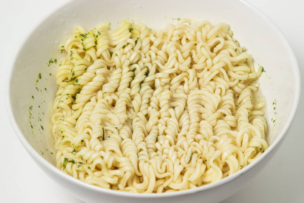 Ξηρά στιγμιαία noodles σε ένα πιάτο σε λευκό φόντο. Φάστφουντ. Σύγχρονο φαγητό. - Φωτογραφία, εικόνα