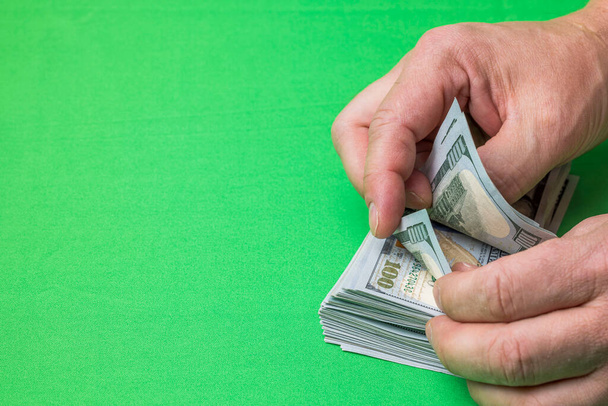View of man's hands counting dollar banknotes on green background. - Photo, Image