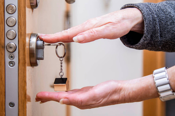 hands showing lock with key and keychain little house - 写真・画像