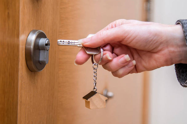 woman hands with key and door lock - Foto, afbeelding