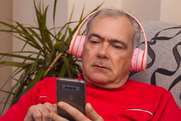 relaxed adult man with headphones and smartphone at home - Fotó, kép