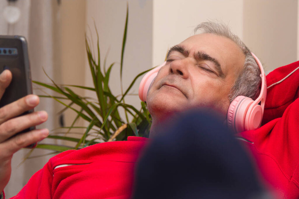 relaxed mature man with headphones and smartphone at home - Фото, зображення