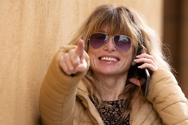adult woman talking on mobile phone while she pointing with her finger - Photo, Image