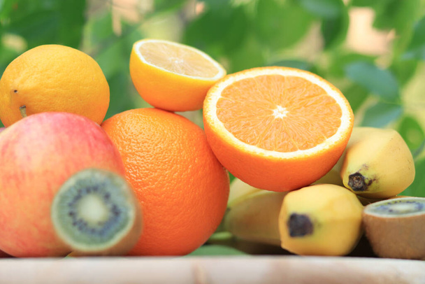 A group of ripe fruits photographed with selective focus. Oranges, kiwi, lemons, apple, bananas, some are cut - Фото, зображення
