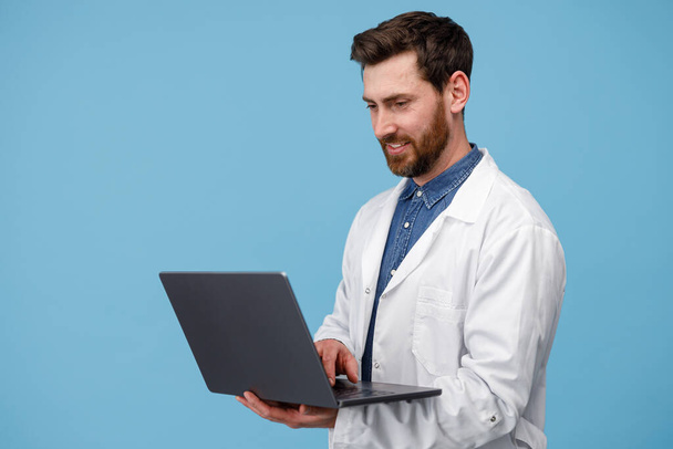 Médico en uniforme blanco lleva a cabo consultas en línea con el paciente en fondo de estudio azul - Foto, imagen