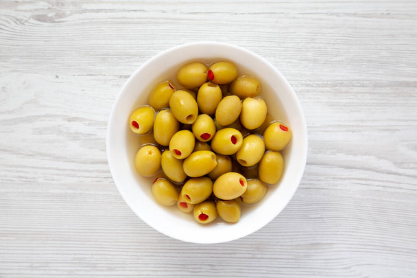 Marated Green Olives with Pimento Peppers in a Bowl, top view (англійською). Плоть лежала, вгорі, зверху..  - Фото, зображення