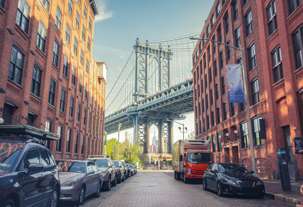 Manhattan Bridge między Manhattanem a Brooklynem nad East River widziany z wąskiej uliczki otoczonej dwoma murowanymi budynkami w słoneczny dzień w Washington Street w Dumbo, Brooklyn, NYC - Zdjęcie, obraz