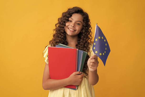 onnellinen teini tyttö opiskella koulun työkirjoja järjestää Euroopan unionin lippu, Schengen viisumi. - Valokuva, kuva