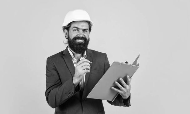 happy bearded man in hard hat at construction site with documents, architect. - Φωτογραφία, εικόνα