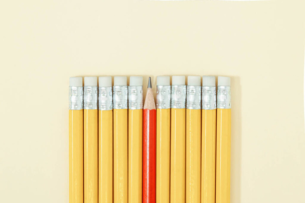 Creative composition with properly lined yellow pencils and one red pencil on pastel sandy background. Be different concept. - Foto, Imagem