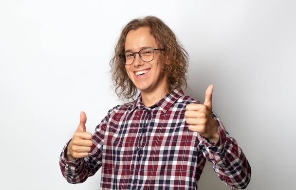 Successful young man with glasses, student, shows a gesture of satisfaction, thumbs up. - Foto, immagini
