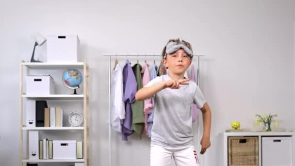 Menino de 9 anos vestido com pijama e máscara de dormir está dançando na sala de estar. Movimento lento. Imagens 4k de alta qualidade - Filmagem, Vídeo