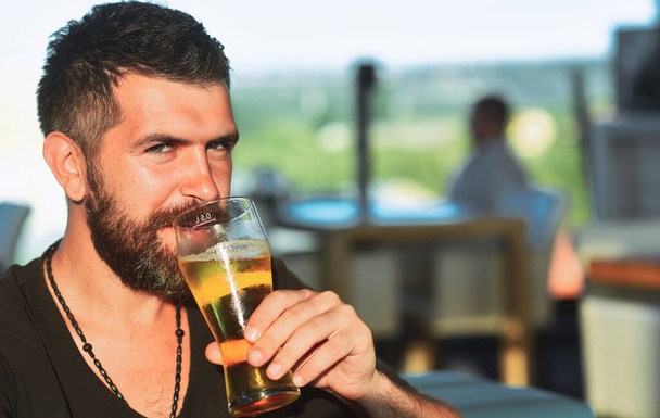 Bearded man with a glass of beer. Beer. Cheerful young man holding glass of beer and looking at camera - Foto, imagen