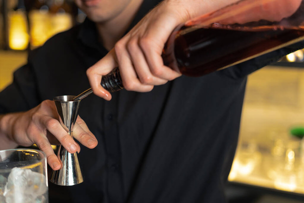бармен готовит коктейль в баре, клубе. наливает алкоголь и сиропы. использует лед и разрывы льда - Фото, изображение