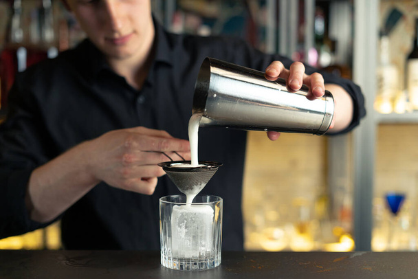 bartender prepares a cocktail in a bar, club. pours alcohol and syrups. uses ice and breaks ice - Photo, image