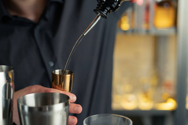 O barman prepara um cocktail num bar, num clube. derrama álcool e xaropes. usa gelo e quebra gelo - Foto, Imagem