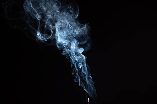 Varilla de incienso con humo contra fondo negro
 - Foto, Imagen