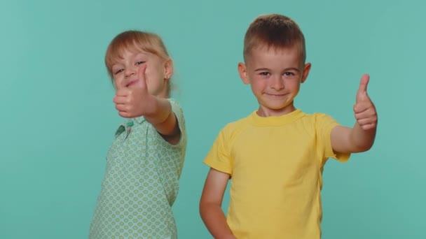 Mint például. Kis kisgyermek fiú és lány testvérek vagy barátok felemeli hüvelykujját egyetért valamivel, vagy ad pozitív választ azt javasolja, reklám jó. Fiatal óvodások kék háttér - Felvétel, videó