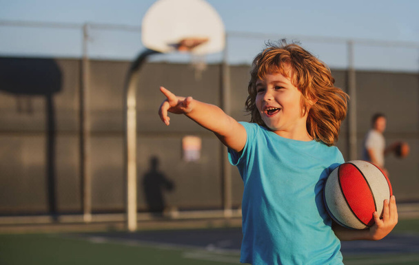 Kid playing basketball with basketball ball. Child pointing showing gesture - Foto, afbeelding