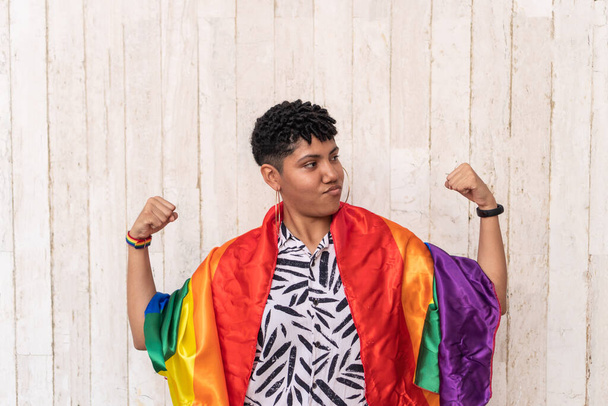 Mujer afro con los brazos extendidos sosteniendo la bandera del arco iris - Foto, Imagen