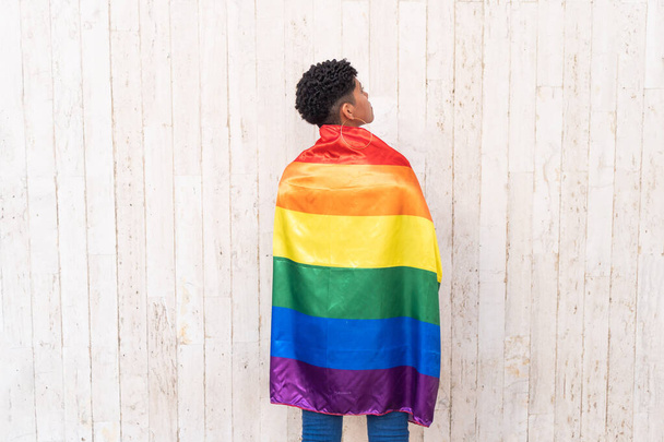 Αφρο γυναίκα κρατώντας γκέι σημαία υπερηφάνειας της σε ένα δρόμο - Φωτογραφία, εικόνα