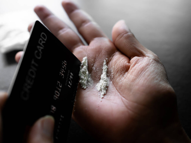 Kokain verteilt auf Handfläche mit verschwommener Kreditkarte. Suchtmittel, Betäubungsmittel, gewohnheitsbildende Substanzen. - Foto, Bild