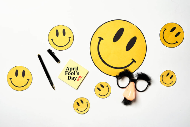 Brille mit Schnurrbart und gelbem Lächeln, 1. April, Scherz, Narrentag, Draufsicht, Großaufnahme auf weißem Untergrund. Text Aprilscherz - Foto, Bild
