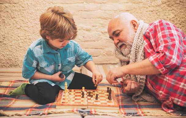 Generations. Checkmate. Chess hobbies - granddad with grandson on a playing chess - Photo, Image