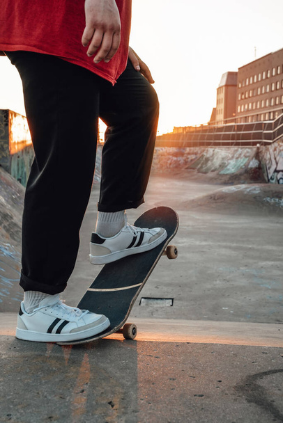 Ritratto di giovane skater vestito in abbigliamento casual con skateboard allo skatepark. - Foto, immagini