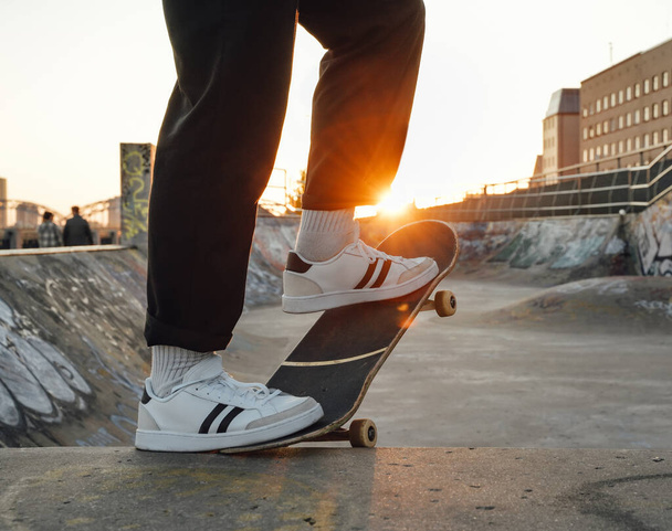 Ritratto di giovane skater vestito in abbigliamento casual con skateboard allo skatepark. - Foto, immagini
