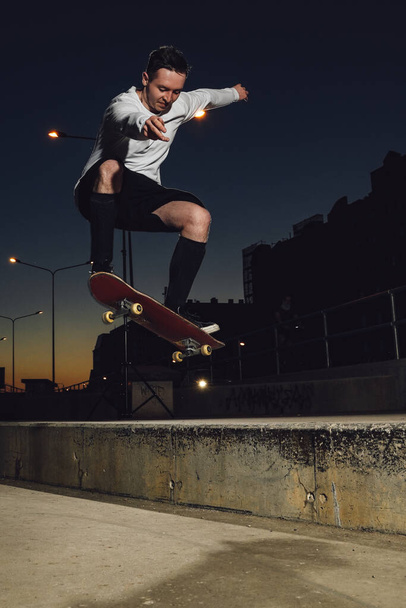 Portret van professionele skateboarder gekleed in witte casual kleding springen skateboard. - Foto, afbeelding