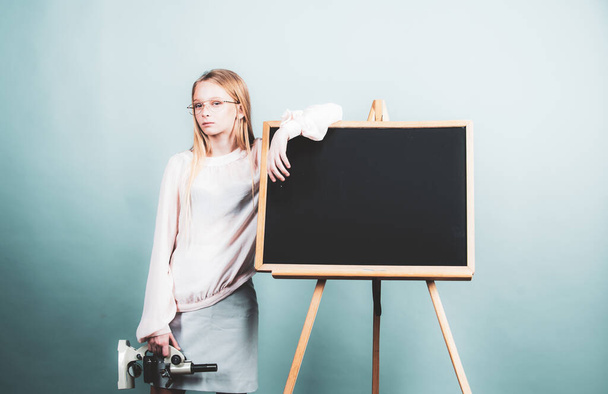Teenager girl student. Attractive little girl holding microscope. Portrait of modern teen school girl near blackboard - Foto, Imagem
