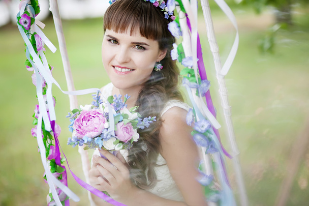 The beautiful bride on a swing under a tree - Fotografie, Obrázek
