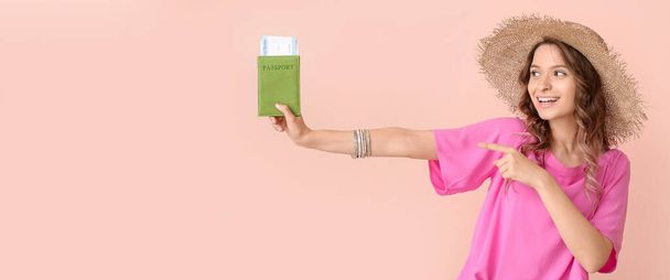 Beautiful female tourist holding passport and tickets on pink background with space for text - Foto, afbeelding