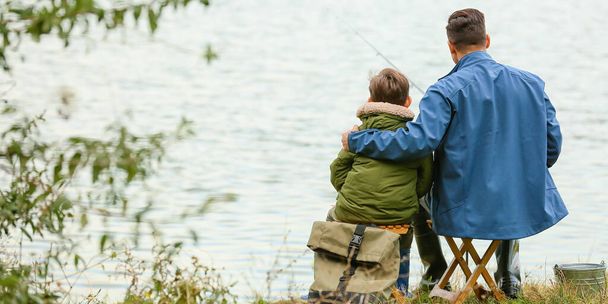 Little boy and his father fishing on river, back view - Foto, Bild