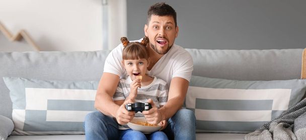 Father and his little daughter playing video games at home - 写真・画像
