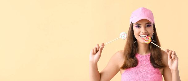 Bella giovane donna con dolci lecca-lecca su sfondo beige con spazio per il testo - Foto, immagini