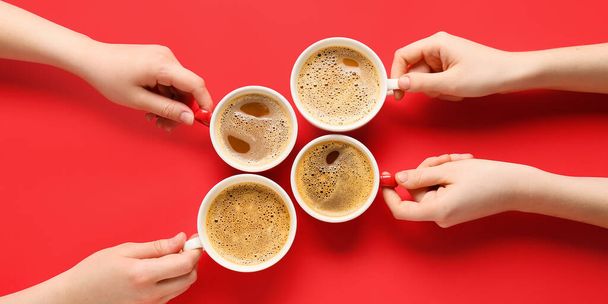 Female hands and cups of coffee on red background, top view - Photo, Image