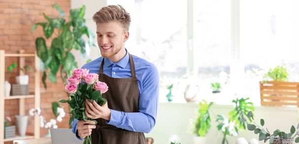 Jeune fleuriste masculin avec bouquet de roses dans la boutique - Photo, image