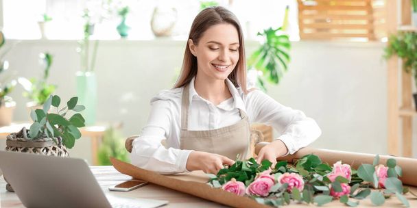 Young female florist working in shop - Фото, изображение