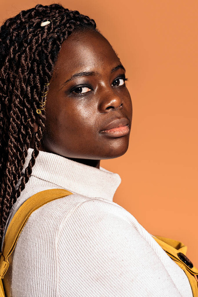 Stock photo of confident black woman with braids posing in studio shot against brown background. - Fotó, kép