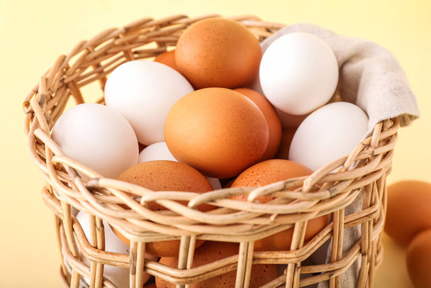 Ψάθινο καλάθι με αυγά κοτόπουλου στο φόντο χρώμα, closeup - Φωτογραφία, εικόνα