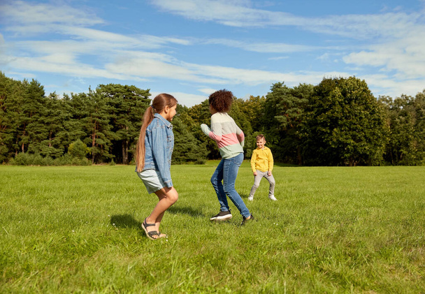 childhood, leisure and people concept - group of happy kids playing tag game and running at park - Zdjęcie, obraz
