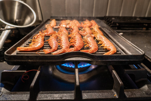Fresh, juicy shrimp on a hot plancha. The seafood steams on the cast-iron, black grill plate. - Photo, image