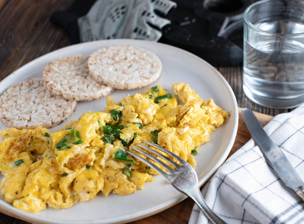 Kolay, basit ve zahmetsiz vücut geliştirme kahvaltısı çırpılmış yumurta, soğan ve kahverengi pirinç krakeriyle. - Fotoğraf, Görsel