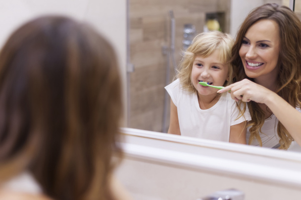 Mother teaches daughter to brush teeth - Φωτογραφία, εικόνα