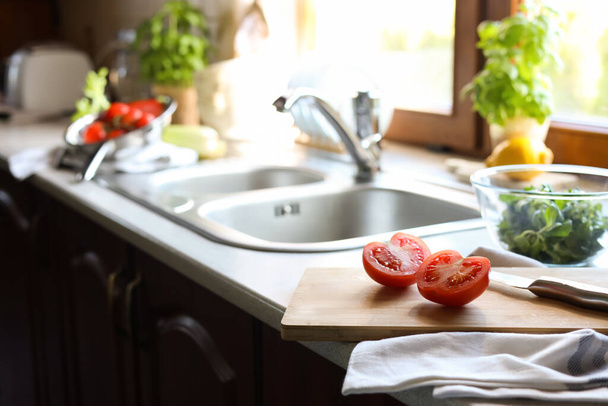 Halves of fresh raw tomato and knife on countertop in kitchen, space for text - Fotó, kép