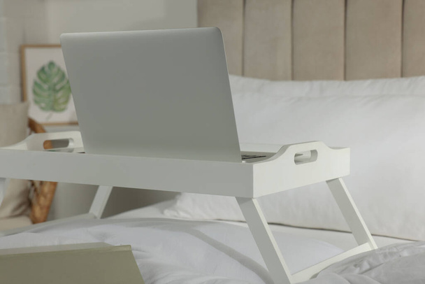 White tray with modern laptop and smartphone on bed indoors - Zdjęcie, obraz